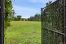 Extended backyard with open field with playground in far corner adjacent to elementary school