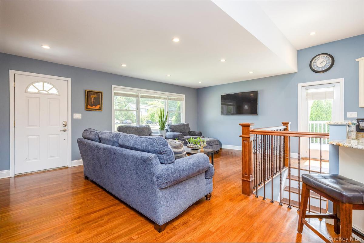 Bright, open living area showcasing gleaming wood-finish flooring throughout, recessed ceiling lighting, and soft blue-gray wall finishes