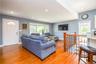 Bright, open living area showcasing gleaming wood-finish flooring throughout, recessed ceiling lighting, and soft blue-gray wall finishes