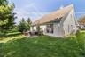Expansive backyard featuring a stone patio, manicured lawn, and mature trees