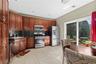 Wood-finish cabinetry with stainless steel appliances, black countertops, and a tile floor