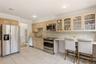 Kitchen featuring stainless steel appliances, light-toned cabinetry, a built-in breakfast bar, granite countertops, and tiled flooring