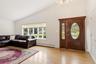 Hardwood flooring, vaulted ceiling, large picture window, and an ornate front door with sidelight