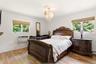 Hardwood-style flooring, white walls, two large windows, and a decorative chandelier
