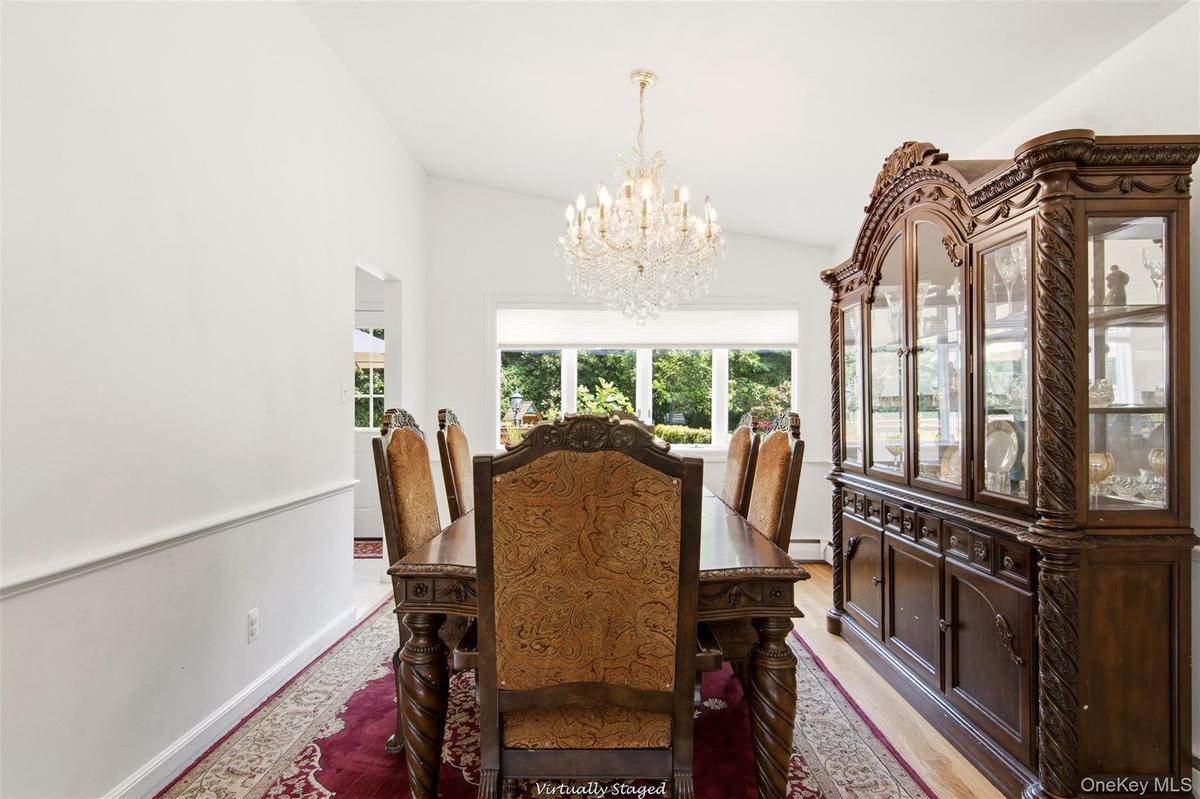 Vaulted ceiling with a crystal chandelier, bay window, and wood-finish flooring