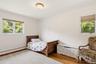 Natural light from multiple windows, wood-finish flooring, and a flush mount ceiling light fixture