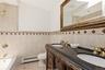Dual vanity with dark countertop, ornate wood-finish cabinetry, and gold-tone fixtures