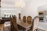 Vaulted ceiling with a crystal chandelier, wood-finish flooring, bay window, kitchen with stainless steel appliances, and wood cabinetry