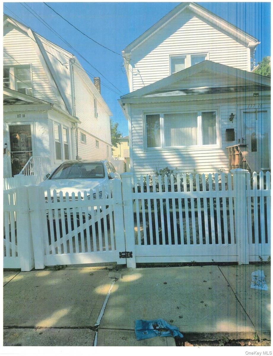 White picket fence with gate, concrete pathway, and residential exterior featuring updated horizontal siding