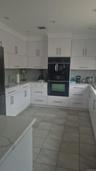 White cabinetry, stone-finish countertops, tile flooring, built-in wall oven, and built-in microwave and dishwasher