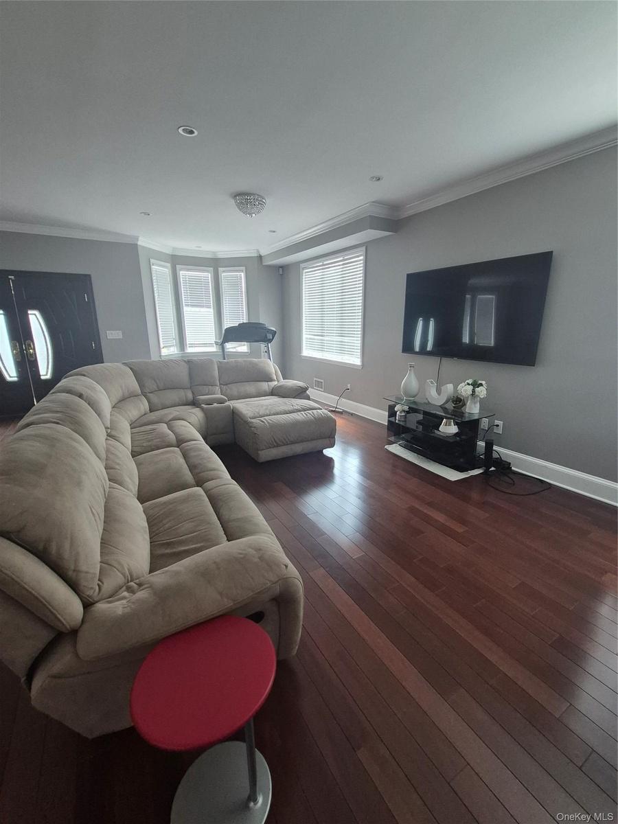 Hardwood flooring, crown molding, bay window, recessed lighting, and crystal chandelier