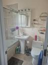Pedestal sink with chrome faucet, wall-mounted medicine cabinet with integrated lighting, tiled shower surround with glass enclosure, wall-mounted hex