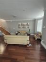 Spacious living room area with hardwood flooring, recessed lighting, crown molding, and a large window with blinds