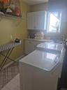 Laundry area with light-colored cabinetry, a utility sink, and a window with washer/dryer combo.