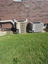 Brick exterior with two HVAC units and a ground-level window and landscaped yard area