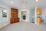 Built-in wood shelving, a ceiling fan with integrated lighting, recessed ceiling lighting, a built-in wet bar with cabinetry, and a large window