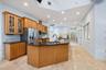 Kitchen with wood cabinetry, granite countertops, stainless steel appliances, a center island with an integrated sink, and recessed lighting