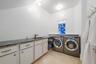 Laundry area with a vaulted ceiling, durable tile flooring, and a long countertop with an undermount sink