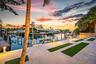 Waterfront property featuring dock access, integrated lighting, and palm trees