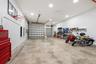 Spacious garage featuring polished concrete flooring, overhead lighting, wall-mounted storage cabinetry, a basketball hoop, and ample room for multipl