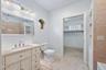 Vanity with integrated sink, contemporary wall-mounted lighting, recessed mirror, and a unique circular window