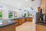 Kitchen featuring a vaulted ceiling with multiple geometric windows, recessed lighting, wood cabinetry, granite countertops, and tile flooring