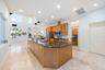 Kitchen featuring a large island with granite countertop, wood cabinetry, stainless steel appliances, and recessed lighting