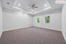 Recessed lighting, ceiling fan, two windows, tray ceiling, and neutral carpet