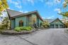 Contemporary exterior with a multi-level roofline, extensive driveway, attached three-car garage, and established landscaping