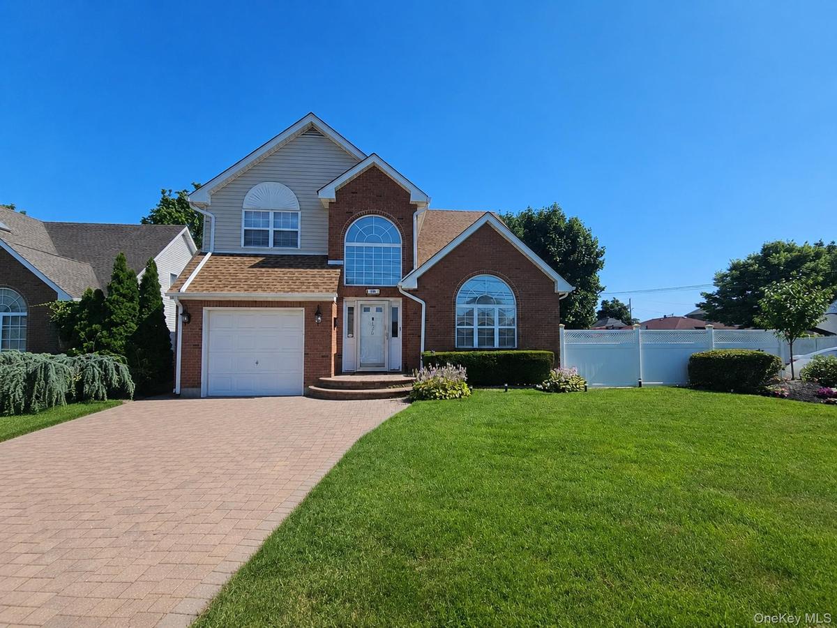 Brick and siding exterior with arched windows, a paver driveway, and a manicured lawn