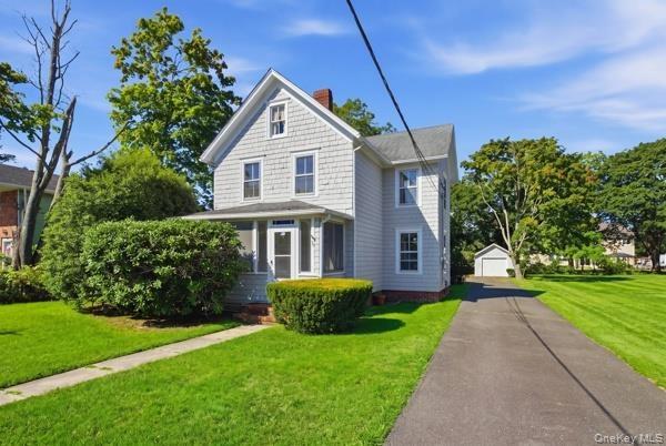 Two-story residence with shingle siding, a screened porch, and a paved driveway leading to a detached garage