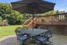 Brick paver patio with a wood deck, wood railings, and lattice skirting, featuring a spacious grass yard