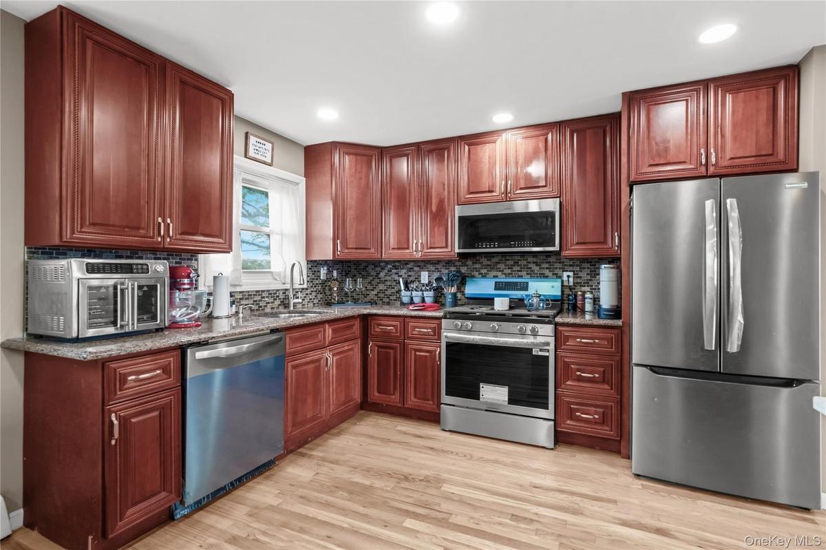 Full complement of stainless steel appliances, wood-finish flooring, wood cabinetry, granite countertops, and tile backsplash