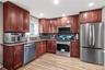 Full complement of stainless steel appliances, wood-finish flooring, wood cabinetry, granite countertops, and tile backsplash