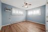 2nd. bedroom Hardwood flooring, ceiling fan, window treatments, and a wall-mounted air conditioning unit