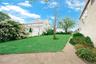 Expansive lawn, mature landscaping, paved pathway, and a privacy fence