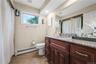 Bathroom featuring a wood-finish vanity with a granite countertop, undermount sink, and tile flooring