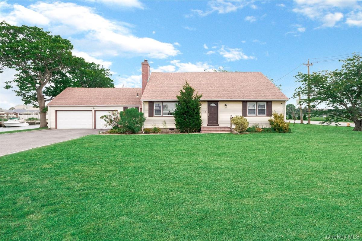 Expansive front lawn, two-car garage, paved driveway, mature trees, and a brick chimney