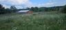 Expansive green fields, red barn with a metal roof, and white perimeter fencing