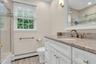 Bathroom featuring a baseboard heating unit, vanity, toilet, bath / shower combo with glass door, and wood finished floors