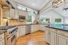 Kitchen with stainless steel appliances, range hood, light wood-style floors, dark countertops, and crown molding