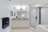 The primary bathroom is spacious with double sinks, a glass shower enclosure and a jetted, deep tub.