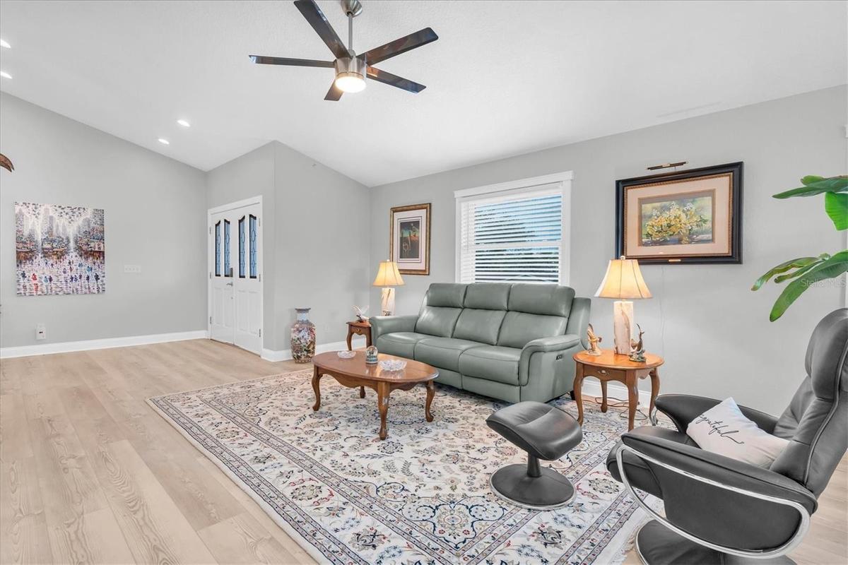 Spacious and light-filled living room with high ceilings, offering a warm and inviting setting for relaxing or entertaining.