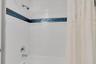 The shower area is surrounded by porcelain tile with attractive blue tile accents.