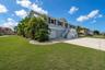 Expansive corner property beautifully framed by lush, mature tropical trees and landscaping.