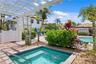 The hot tub is nestled under a charming pergola, surrounded by lush tropical landscaping.