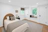 Recessed lighting, wood-finish flooring, two panel doors with black hardware, window with integrated seating, and a second window with a woven shade