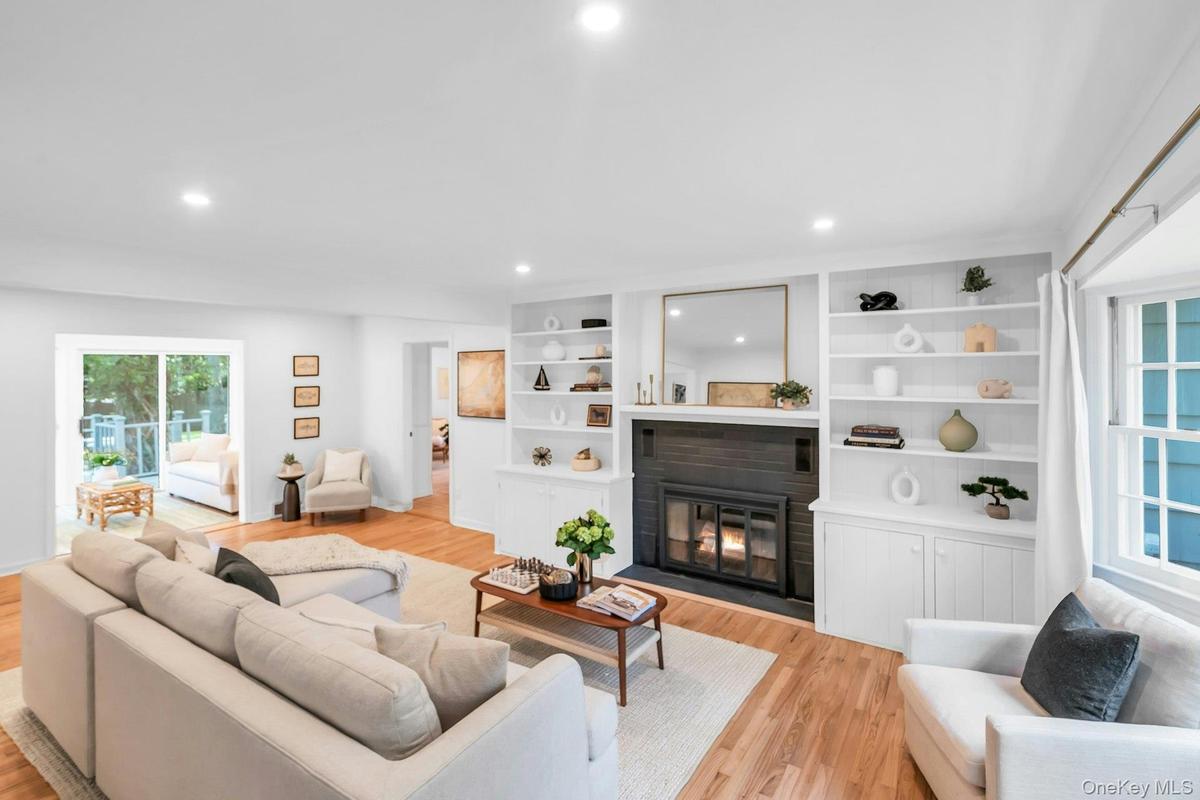 Recessed lighting illuminates wood-finish flooring, a built-in fireplace, and custom shelving
