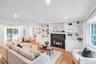 Recessed lighting illuminates wood-finish flooring, a built-in fireplace, and custom shelving