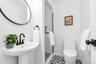 Pedestal sink with matte black faucet, checkered tile flooring, glass-enclosed shower, white toilet, and matte black door hardware
